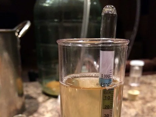 a hydrometer is floating in hard cider that reads 0.996