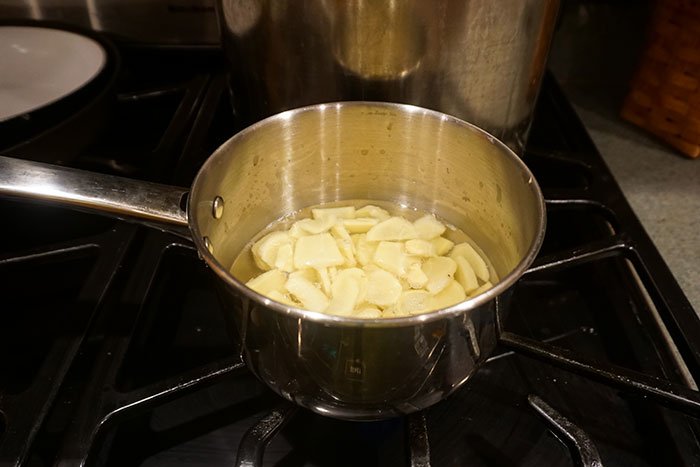 a stainless pot boiling water and ginger for ginger apple cider