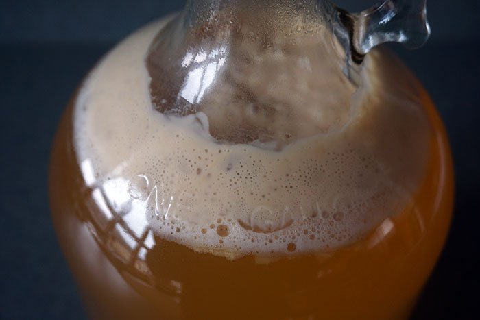 brown foam krausen forming on the top of cider in fermentation