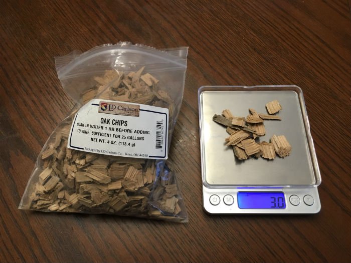 Weigh the oak chips before adding them to hard cider chips of oak wood being weighed on a digital scale before adding them to cider