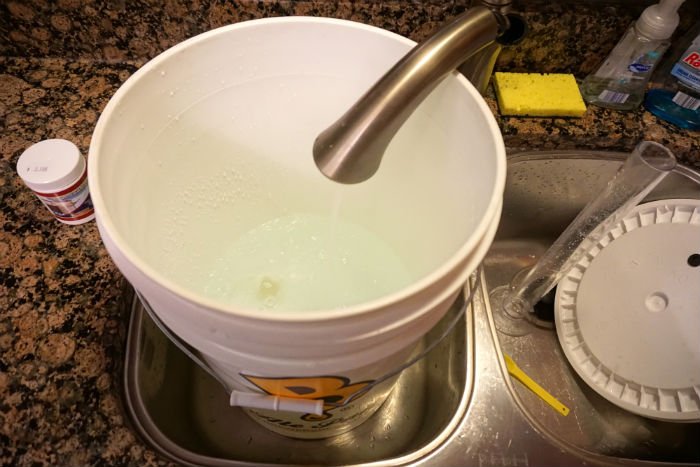 Clean and sanitize all cidermaking equipment a bucket filled with sanitizer in a kitchen sink