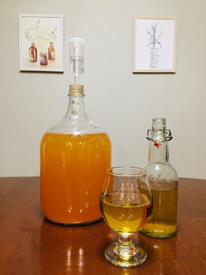 a jug, bottle and glass each with hard cider