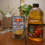 containers of pineapple and apple juice with fermenting equipment