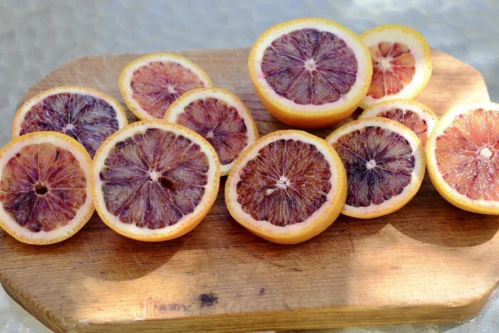 several cut blood oranges on a wooden cutting board